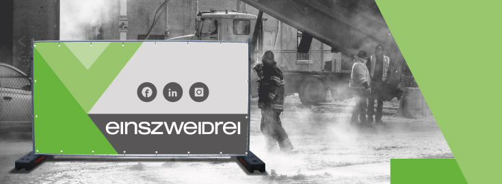 Eine Baustelle mit Arbeitern und Geräten im Hintergrund, teilweise verdeckt durch eine halbtransparente Barriere mit den Logos von Facebook, LinkedIn und Instagram über dem Wort „einszweidrei“ und einem geometrischen grünen Muster.