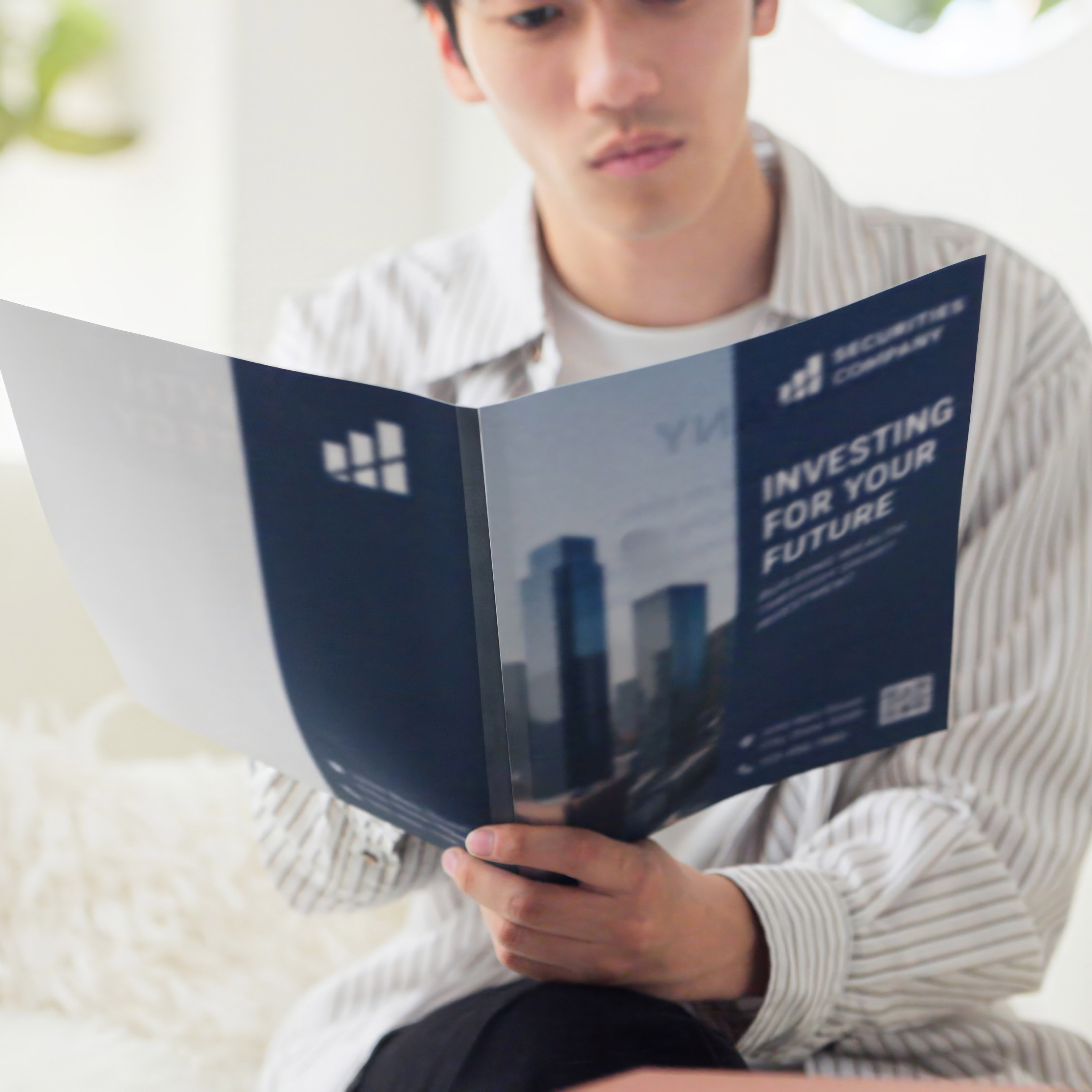 A person sitting indoors is reading a blue brochure titled