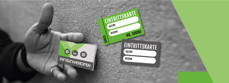 Eine Hand hält eine Visitenkarte mit dem Logo und Social-Media-Symbolen für „einszweidrei“, während zwei Eintrittskarten mit der Aufschrift „EINTRITTSKARTE“ und Feldern für Datum und Startzeit daneben schweben; der Hintergrund ist grau mit grünen geometrischen Akzenten.