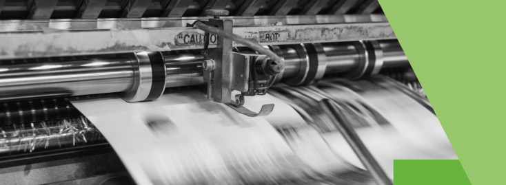 Nahaufnahme einer in Betrieb befindlichen Druckmaschine, bei der Papierbögen schnell durch die Walzen laufen; das Bild ist auf der rechten Seite teilweise mit einer grünen geometrischen Form überlagert.