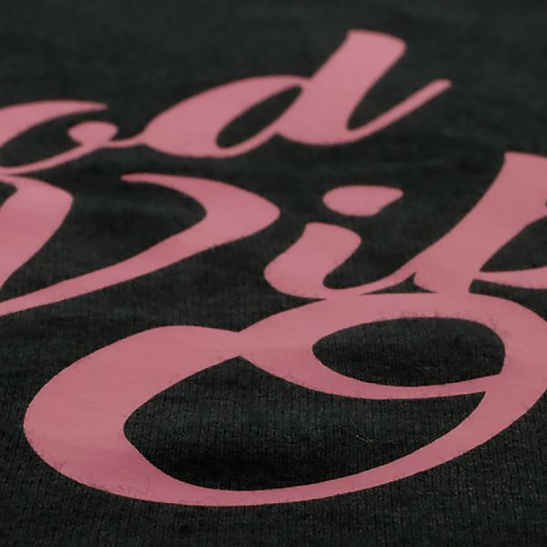 A close-up of pink script lettering on a dark fabric background, showing only partial letters.