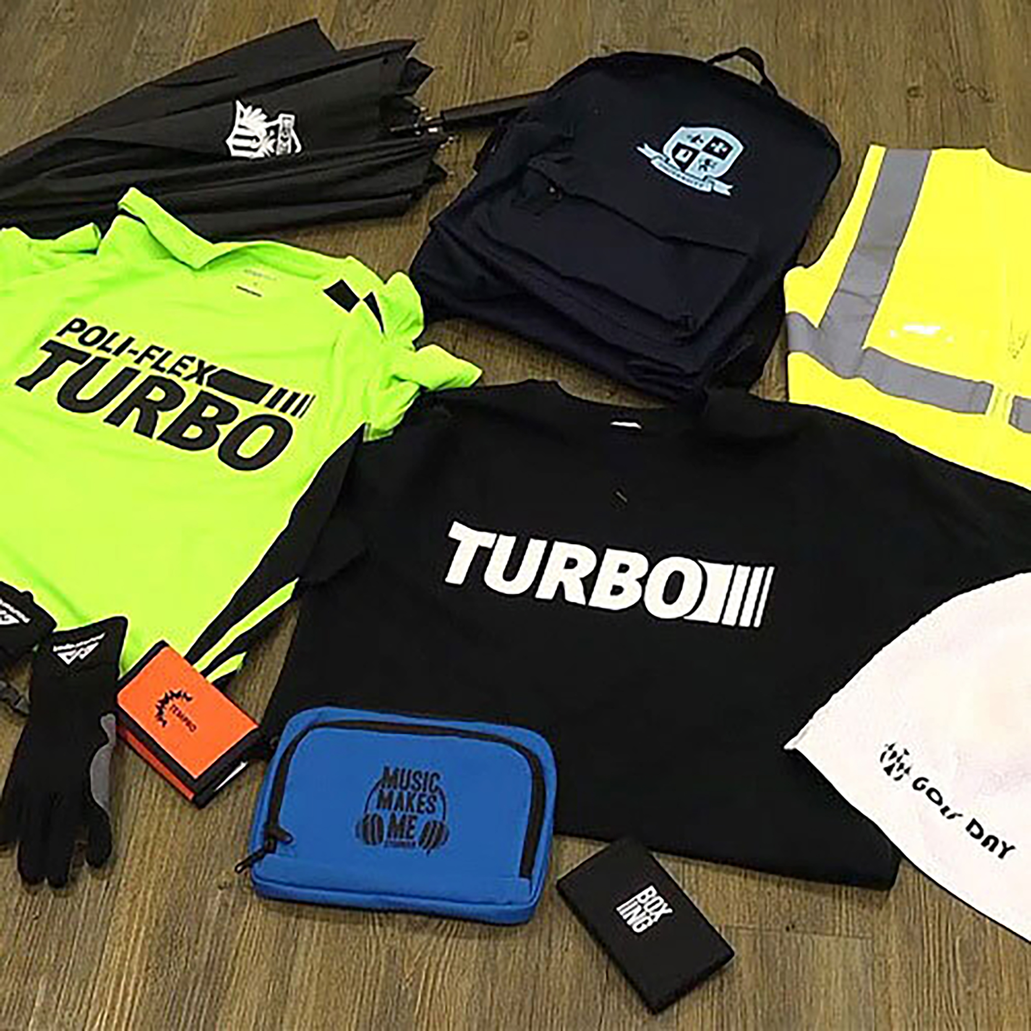 A collection of promotional items arranged on a wooden floor, including a neon yellow 